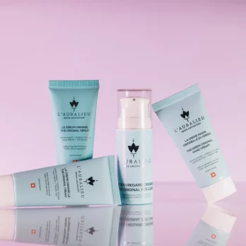 Assortiment de produits de soin L'Aubalieu en format voyage sur fond rose.