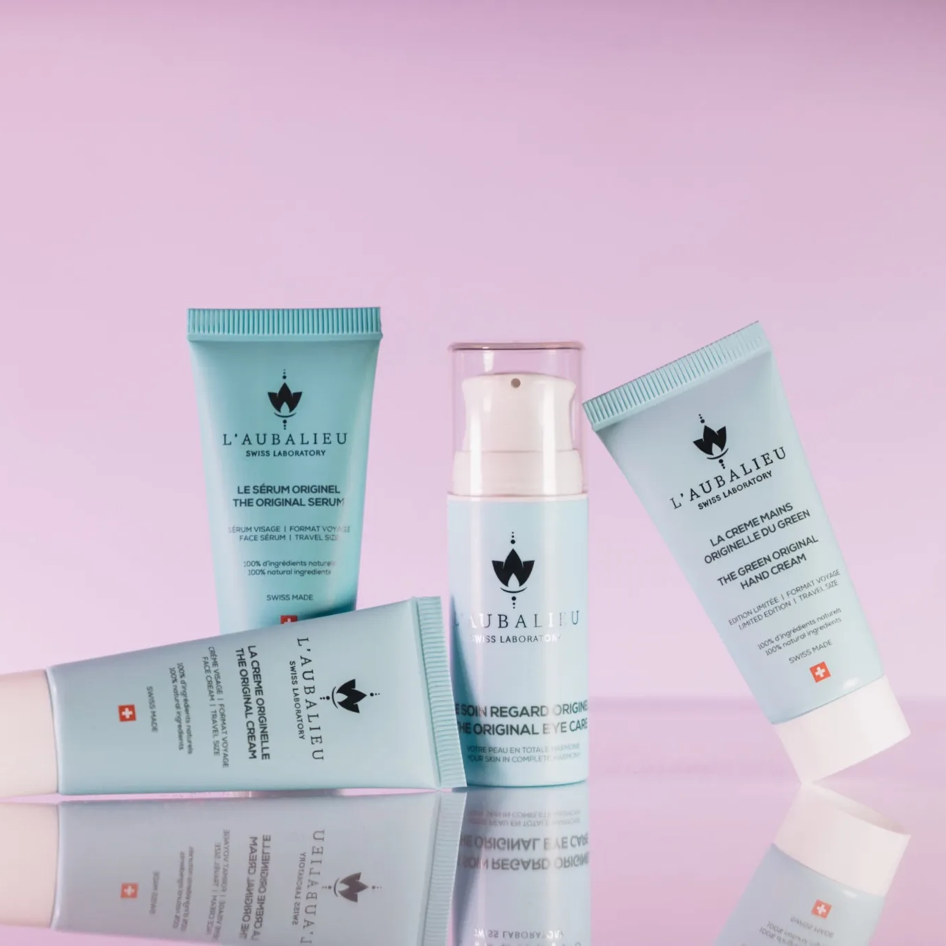 Assortiment de produits de soin L'Aubalieu en format voyage sur fond rose.