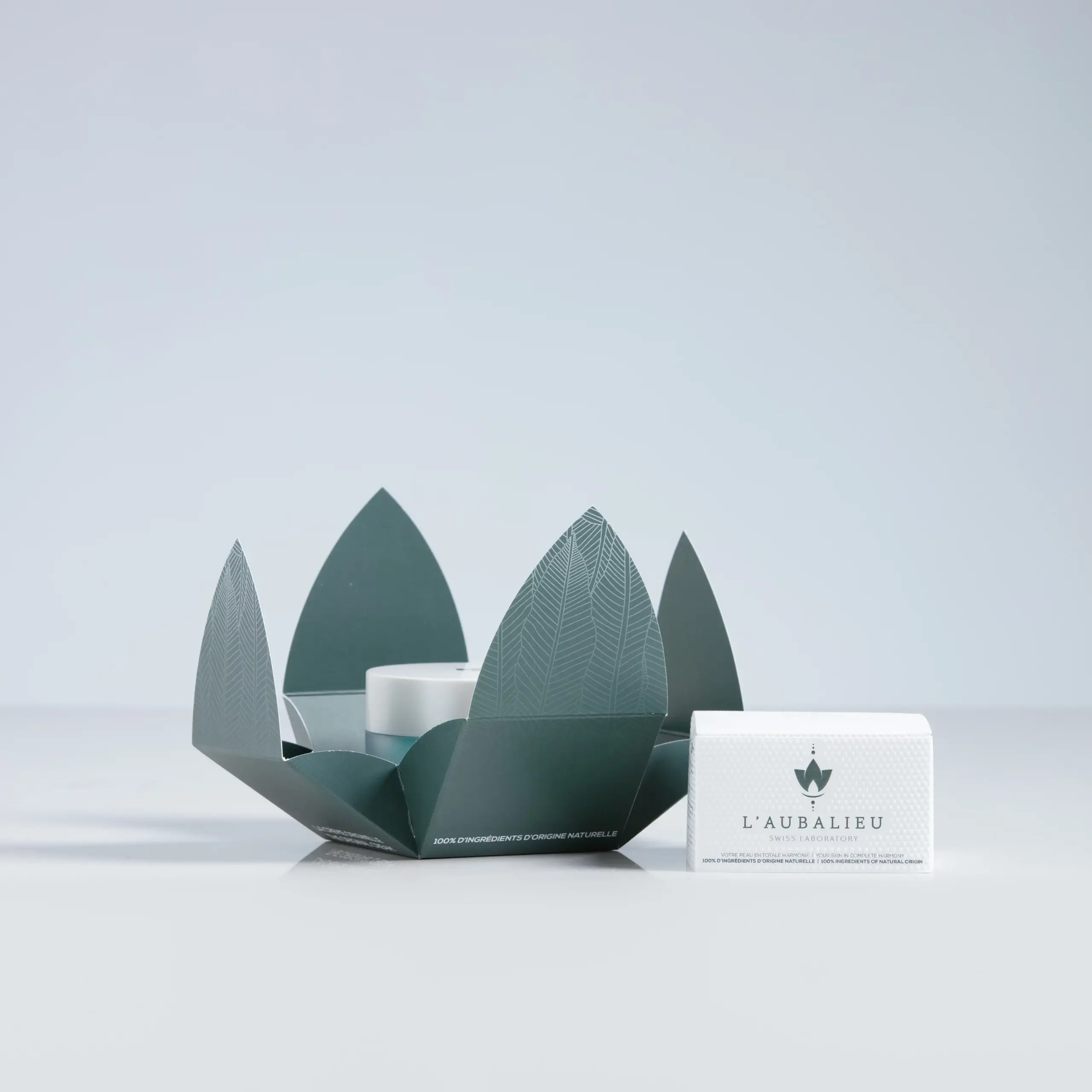 Crème hydratante L'aubalieu présentée dans un écrin de feuilles, incarnant l'innovation et la pureté de la nature