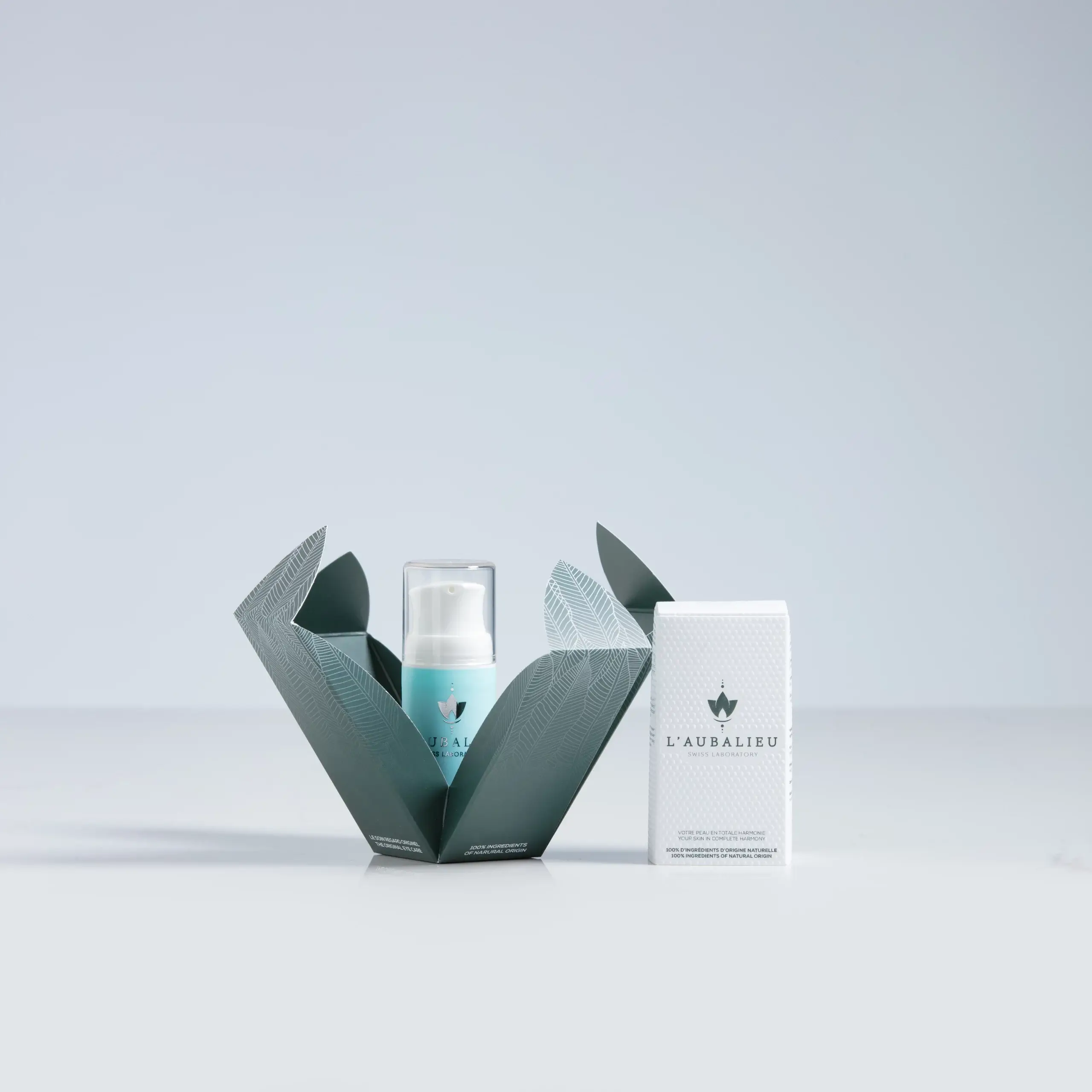 Flacon de phytocosmétique Laubalieu émergeant d'un emballage artistique en forme de feuilles, mettant en avant l'élégance et la naturalité