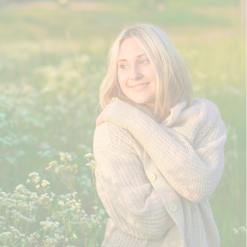 Femme souriante en pull douillet, entourée de nature, incarnant la douceur des soins L'aubalieu